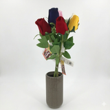 Colorful artificial roses in a ribbed vase on a white background